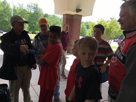 A club volunteer shows a group of students how to use a bike tool
