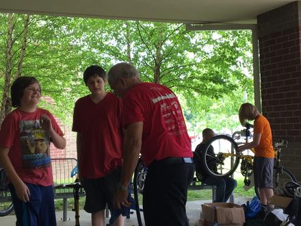 A volunteer talks with students beside a bike repair stand
